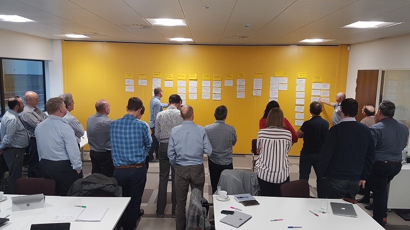 Participants standing up as sticky notes get organised on wall